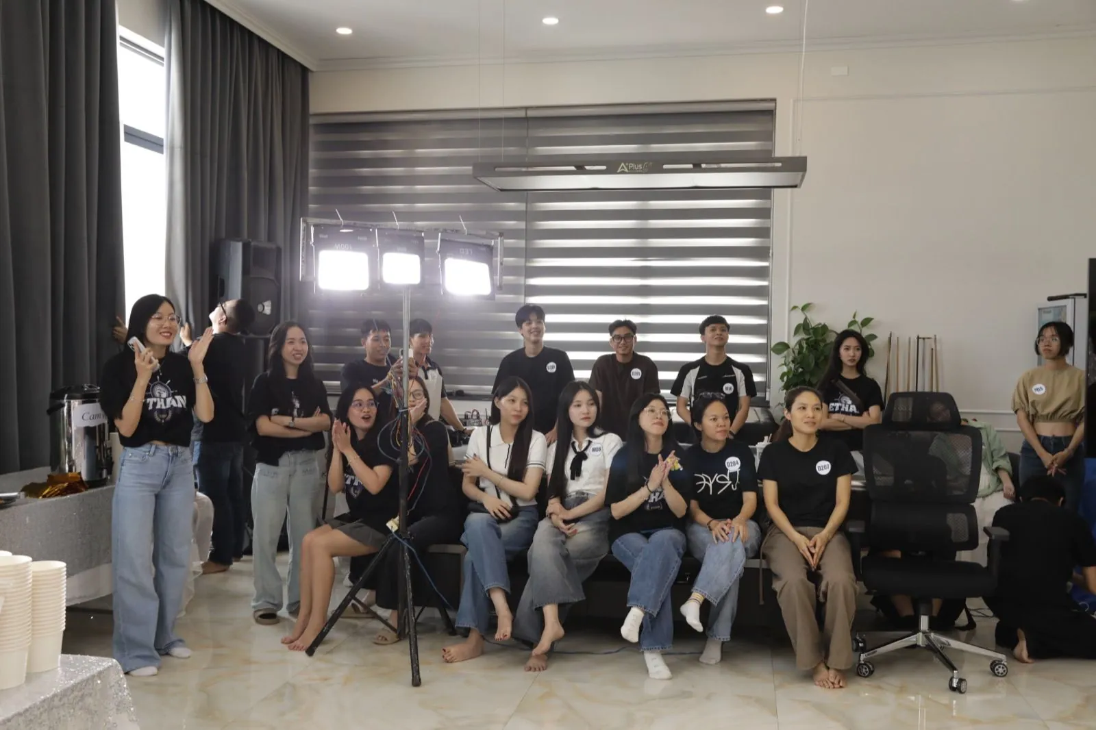 Dàn thí sinh Over Limitation đeo số báo danh chụp ảnh nhóm, vỗ tay dưới ánh đèn studio